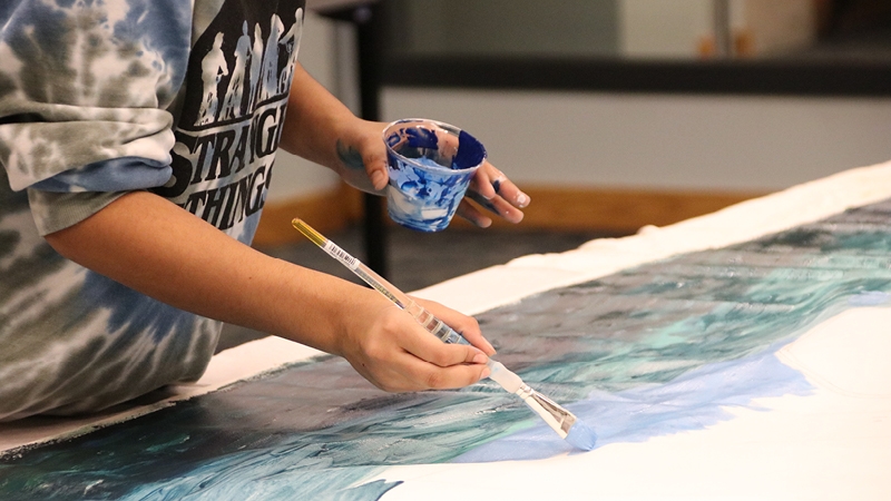 Teen painting with brush and cup